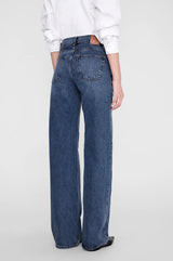 Anine Bing Hugh Jean 34" i dark indigo sett bakfra – wide leg med lang innersøm, paspellomme bak og rå kant, stylet med hvit skjorte og sorte cowboystøvler
