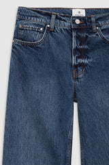 Nærbilde av Anine Bing Hugh Jean 34" i dark indigo – detalj av midjelinningen med sølvknapper, AB-merkelapp i lærlook og vintage-inspirert denim-tekstur
